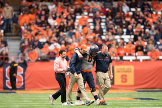 Syracuse center Colin Byrne leaves the field with the help of two trainers.